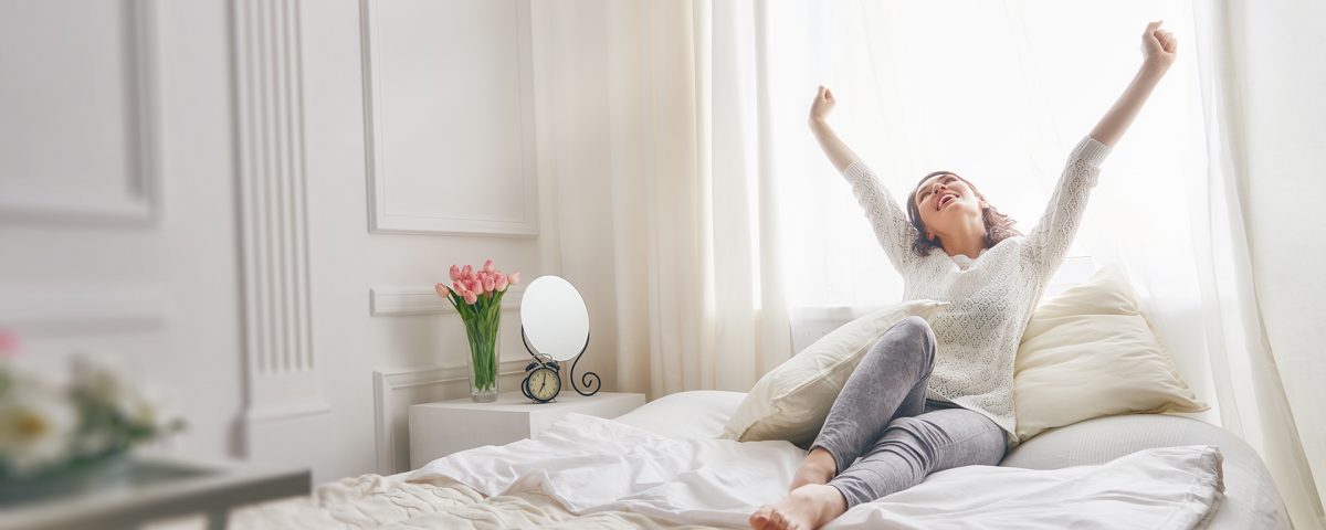 Image d’une femme qui s’étire sur son lit, moment de bien-être pour illustrer l’importance du capital santé»